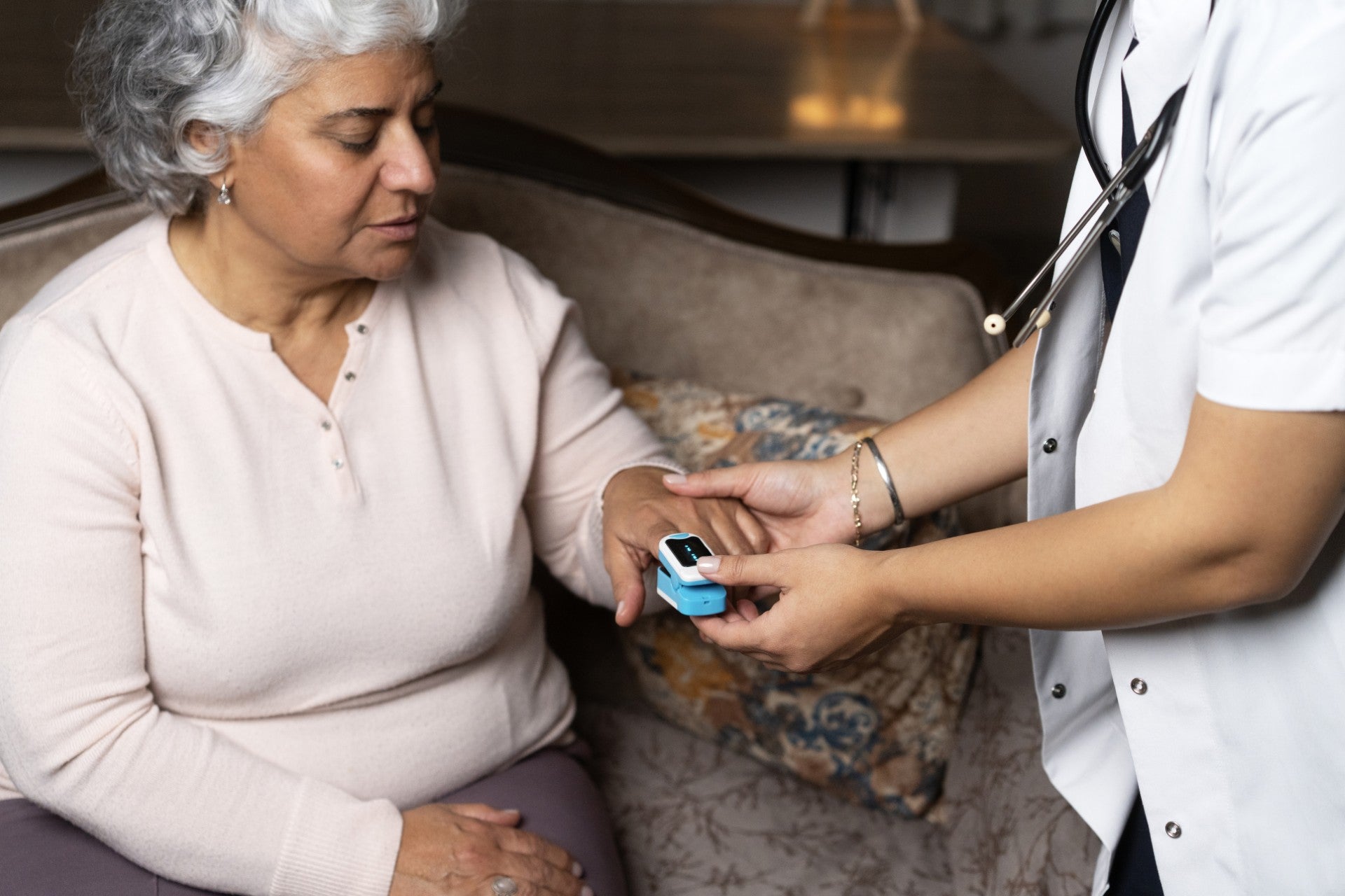 /An%20image%20of%20a%20healthcare%20professional%20putting%20a%20pulse%20oximeter%20on%20a%20woman%27s%20finger%20whilst%20she%20is%20sitting%20down.