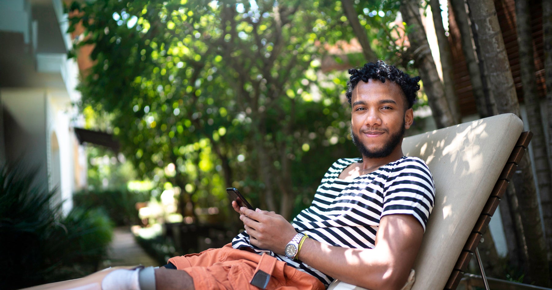 Man lying on deckchair outside with phone in his hand