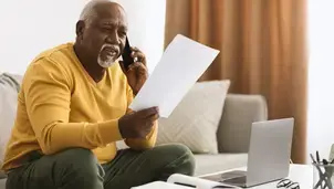 Man wearing a yellow jumper on the telephone