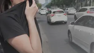 Woman covering her nose and mouth beside a busy road
