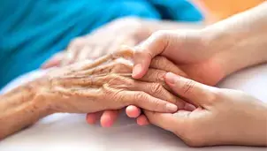 Younger person holding hands with an older person