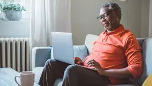 Man on a sofa looking at a laptop