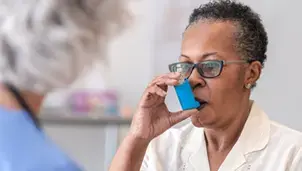 Woman using a blue reliever inhaler