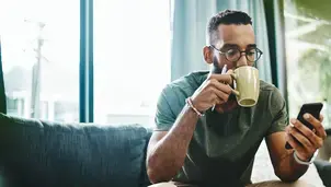 Man drinking coffee and using a phone