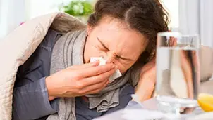 Woman in bed blowing her nose