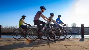 A group of four friends ride their bikes along the quayside