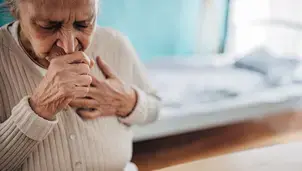 Senior woman coughing while touching her chest