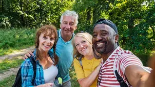 Friends walking on forest footpath, wearing casual clothing and backpacks