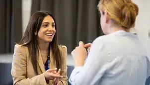 Two people in conversation, one smiling woman facing the camera.