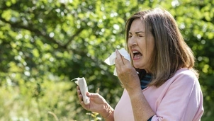 Woman outdoors sneezing into tissue