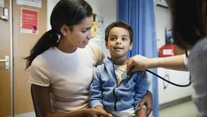 Child sat on their parents lap in a check-up with a doctor
