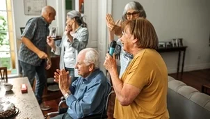 group of perople singing and dancing around a laptop