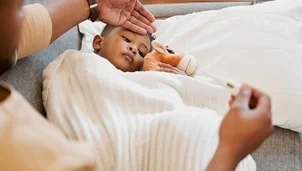 Child lying down with someone holding a thermometer 