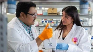 Two people in lab coats holding a sample in a lab