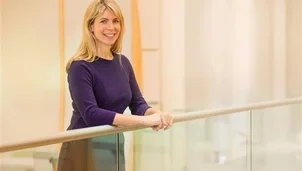 An image of a woman with long blonde hair wearing a dark long sleeved top and smiling to camera.